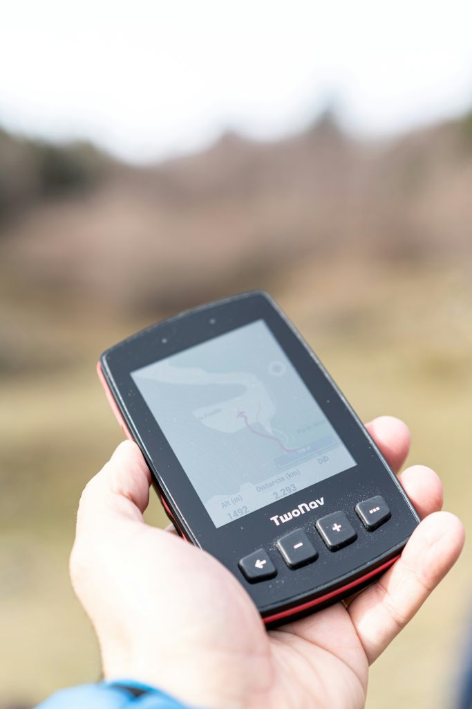 Outdoor enthusiast using handheld GPS device for navigation during mountain hiking adventure